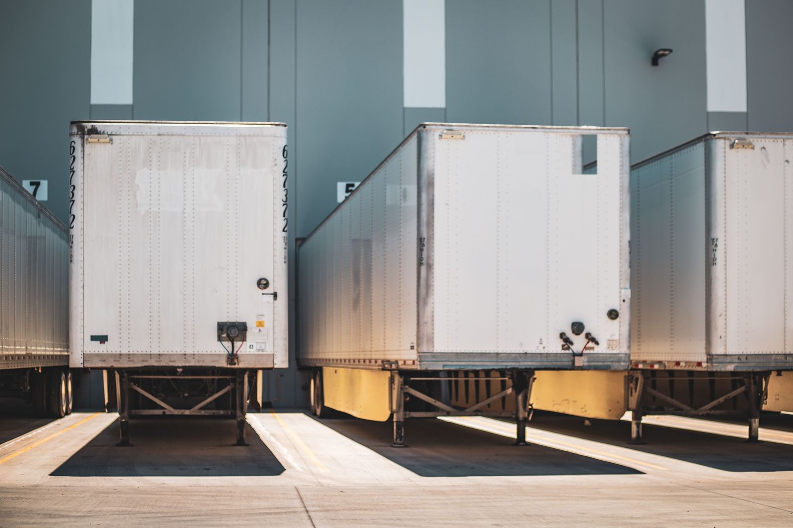 White semi trailers parked at numbered warehouse dock bays